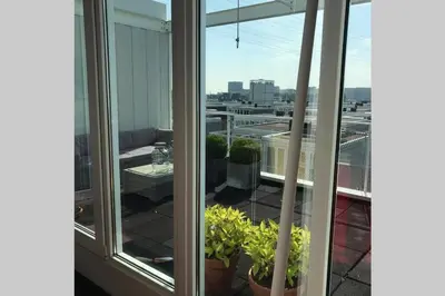 a balcony with a view of a city from a window at Large and cosy house on the water: free Parking in Amsterdam
