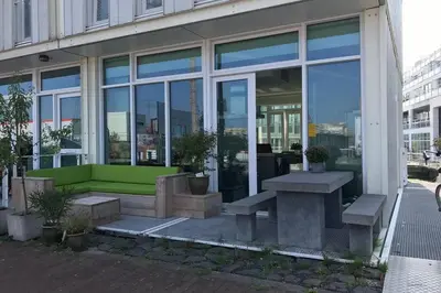 a building with a green bench in front of a building at Large and cosy house on the water: free Parking in Amsterdam