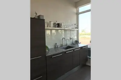 a kitchen with a sink and a large window at Large and cosy house on the water: free Parking in Amsterdam