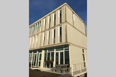 a large white building with a bench in front of it at Large and cosy house on the water: free Parking in Amsterdam
