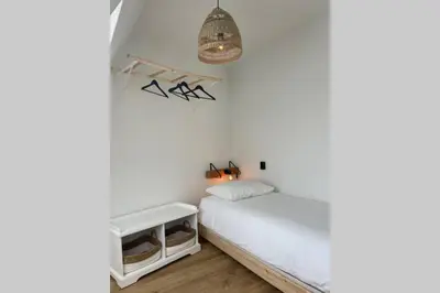 a small bedroom with a white bed and a lamp at Have a nice stay! - Raaff-71 sfeervol huis direct bij bos, duin en strand in Noordwijk