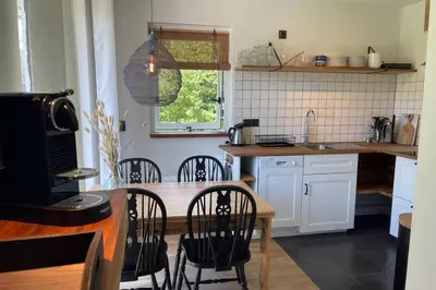 a kitchen with a wooden table and chairs and a counter at Have a nice stay! - Raaff-71 sfeervol huis direct bij bos, duin en strand in Noordwijk