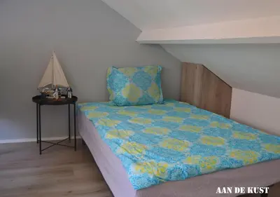 a bedroom with a bed with a blue and yellow quilt at Zomerhuis 