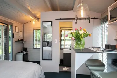 a bedroom with a desk with a vase of flowers at Tiny House Boatshed in Heemstede