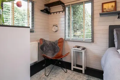 a room with a chair and a table and a clock at Tiny House Boatshed in Heemstede