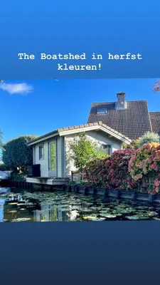a house sitting on a dock next to a river at Tiny House Boatshed in Heemstede