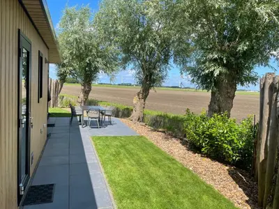 a patio with a table and chairs on the side of a house at Vogelvrij, vakantie woning met landelijk uitzicht en geheel omheinde tuin in Burgerbrug