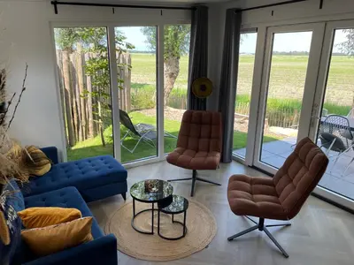 a living room with a couch and two chairs and a table at Vogelvrij, vakantie woning met landelijk uitzicht en geheel omheinde tuin in Burgerbrug