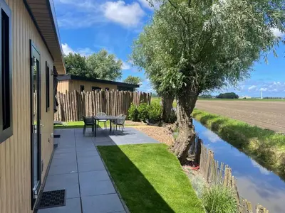 a patio with a table and chairs next to a house at Vogelvrij, vakantie woning met landelijk uitzicht en geheel omheinde tuin in Burgerbrug