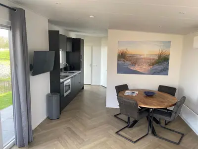 a kitchen with a wooden table and a dining room at Vogelvrij, vakantie woning met landelijk uitzicht en geheel omheinde tuin in Burgerbrug