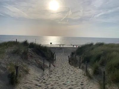 a sandy beach with the sun rising over the ocean at Vogelvrij, vakantie woning met landelijk uitzicht en geheel omheinde tuin in Burgerbrug