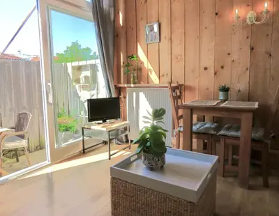 a living room with a tv and a table with a plant at Beachtime close to the beach, city centre in Zandvoort