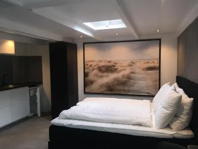 a bedroom with a bed with a painting on the wall at Centre beach lodge (2) in Zandvoort