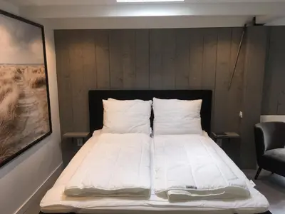 a bed with white sheets and pillows in a room at Centre beach lodge (2) in Zandvoort