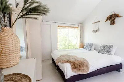 a white bedroom with a bed and a window at Hippie Beach in Zandvoort