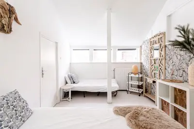 a white bedroom with a bed and a desk at Hippie Beach in Zandvoort