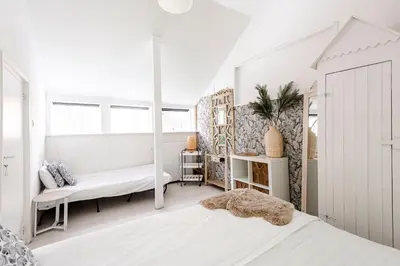 a white bedroom with a bed and a window at Hippie Beach in Zandvoort