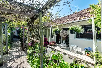 a garden with a wooden table and a pergola at Hippie Beach in Zandvoort