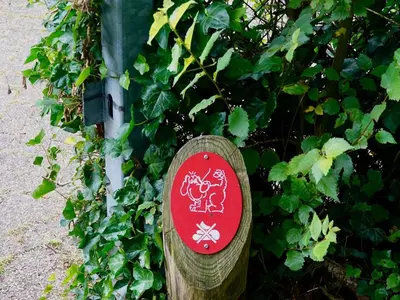 a wooden sign sitting in front of a bush at Family Escape Near Keukenhof in Noordwijkerhout