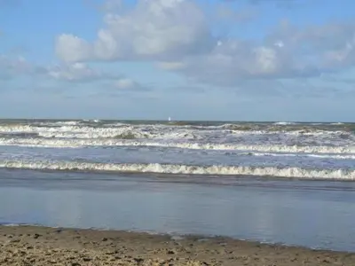 a beach with some waves in the ocean at Family Escape Near Keukenhof in Noordwijkerhout
