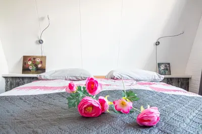 a bed with three pink roses on it at 4T4 Apartment B in Egmond aan den Hoef