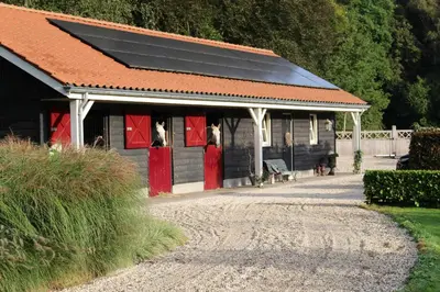 a black and red building with red doors and a bench at Huize Koempoelan in Naarden