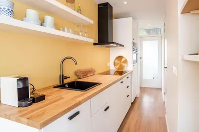 a kitchen with white cabinets and a sink at The Shell Apartment in Zandvoort