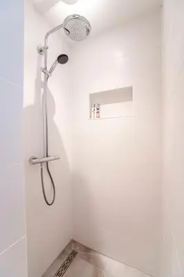 a shower in a bathroom with white walls at The Shell Apartment in Zandvoort