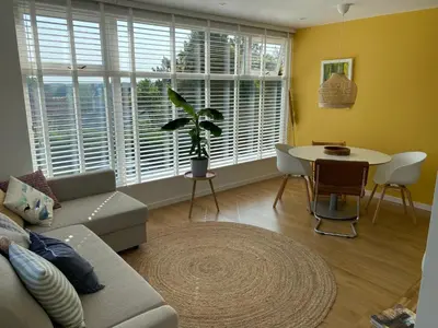 a living room with a couch and a table with a plant at The Shell Apartment in Zandvoort