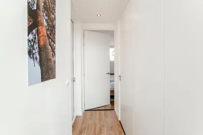 a hallway with white walls and a tree painting on the wall at SeatheDunes in Zandvoort