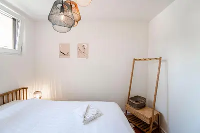 a white bedroom with a bed and a lamp at SeatheDunes in Zandvoort