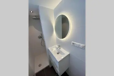 a white bathroom with a sink and a mirror at Stella Maris Dune Apartment in Zandvoort
