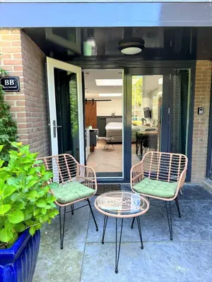 three chairs and a table on a patio at Stella Maris Dune Apartment in Zandvoort