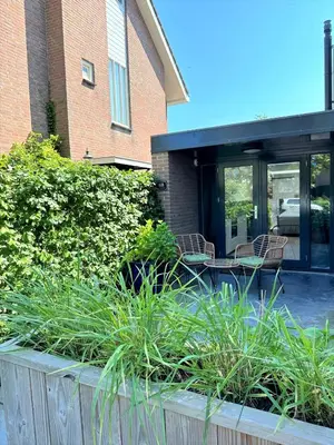 a patio with chairs and plants in front of a building at Stella Maris Dune Apartment in Zandvoort