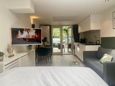 a bedroom with a bed and a living room with a tv at Stella Maris Dune Apartment in Zandvoort