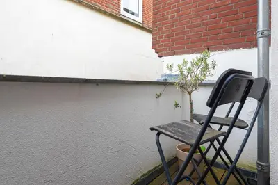 a chair sitting next to a building with a plant at Beach Studio Zen in the Centre of Zandvoort in Zandvoort