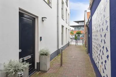a narrow alley with a black door on a white building at Beach Studio Zen in the Centre of Zandvoort in Zandvoort