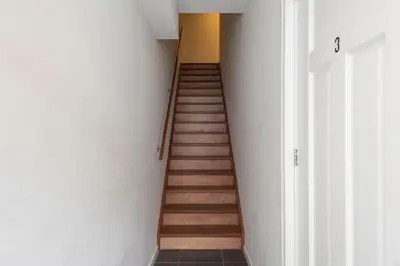 a staircase in a room with white walls and wooden floors at Beach Studio Zen in the Centre of Zandvoort in Zandvoort