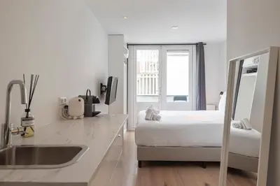 a white kitchen with a bed and a sink at Beach Studio Zen in the Centre of Zandvoort in Zandvoort