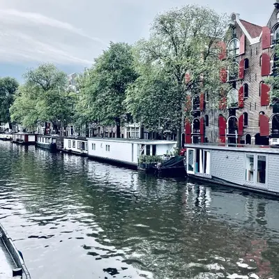 a group of boats on a river in front of buildings at Houseboat Bonnie in Amsterdam