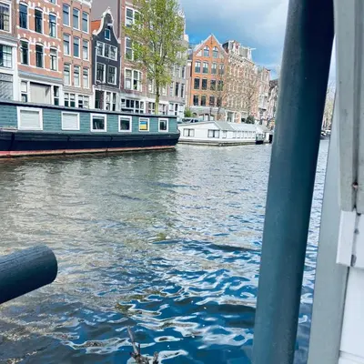 a boat on a river with buildings in the background at Houseboat Bonnie in Amsterdam
