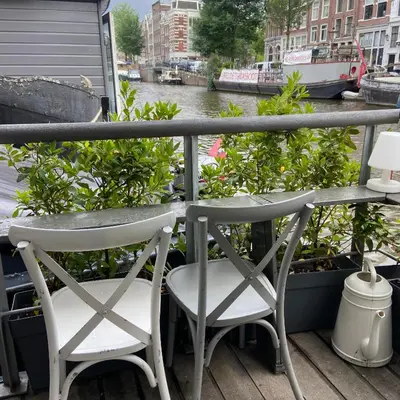 two chairs and a table on a balcony overlooking a canal at Houseboat Bonnie in Amsterdam