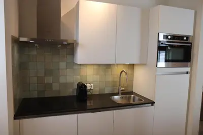 a kitchen with white cabinets and a sink at Guesthouse Bonniehofje in Zandvoort