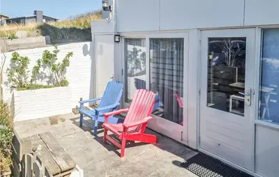 two colorful chairs sitting on the back porch of a house at Windwijser in Bergen aan Zee