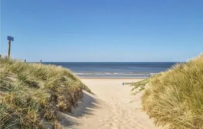 a sandy path leading to a beach with the ocean at Windwijser in Bergen aan Zee