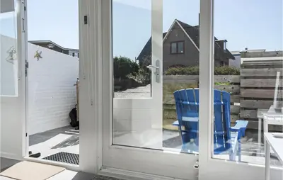 a sliding glass door with a blue chair on a balcony at Windwijser in Bergen aan Zee