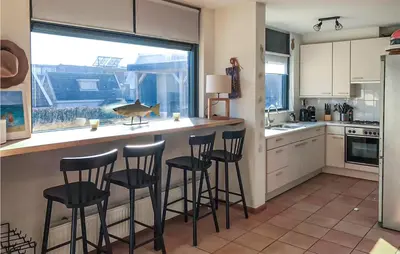 a kitchen with a bar with stools and a bird on the counter at Het Station in Bergen aan Zee