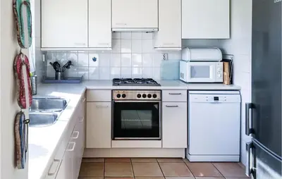 a white kitchen with a stove and a microwave at Het Station in Bergen aan Zee