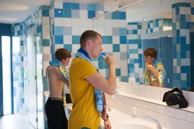a man standing in a bathroom brushing his teeth at Camping Zeeburg Amsterdam in Amsterdam