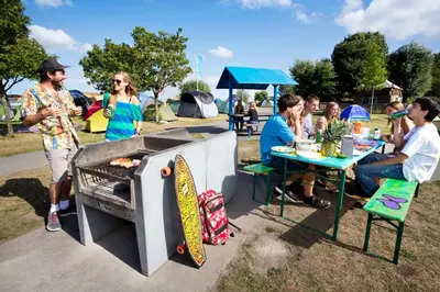 a group of people sitting at a table with a grill at Camping Zeeburg Amsterdam in Amsterdam